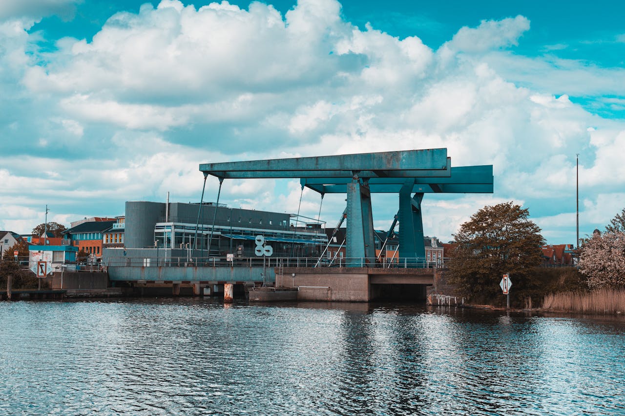 A modern urban scene with industrial structures by the water under a bright blue sky.